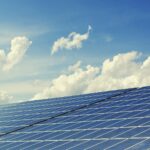 Sleek modern solar panels under a vibrant blue sky with clouds, symbolizing clean energy.