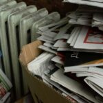 a cardboard box full of newspapers next to a radiator