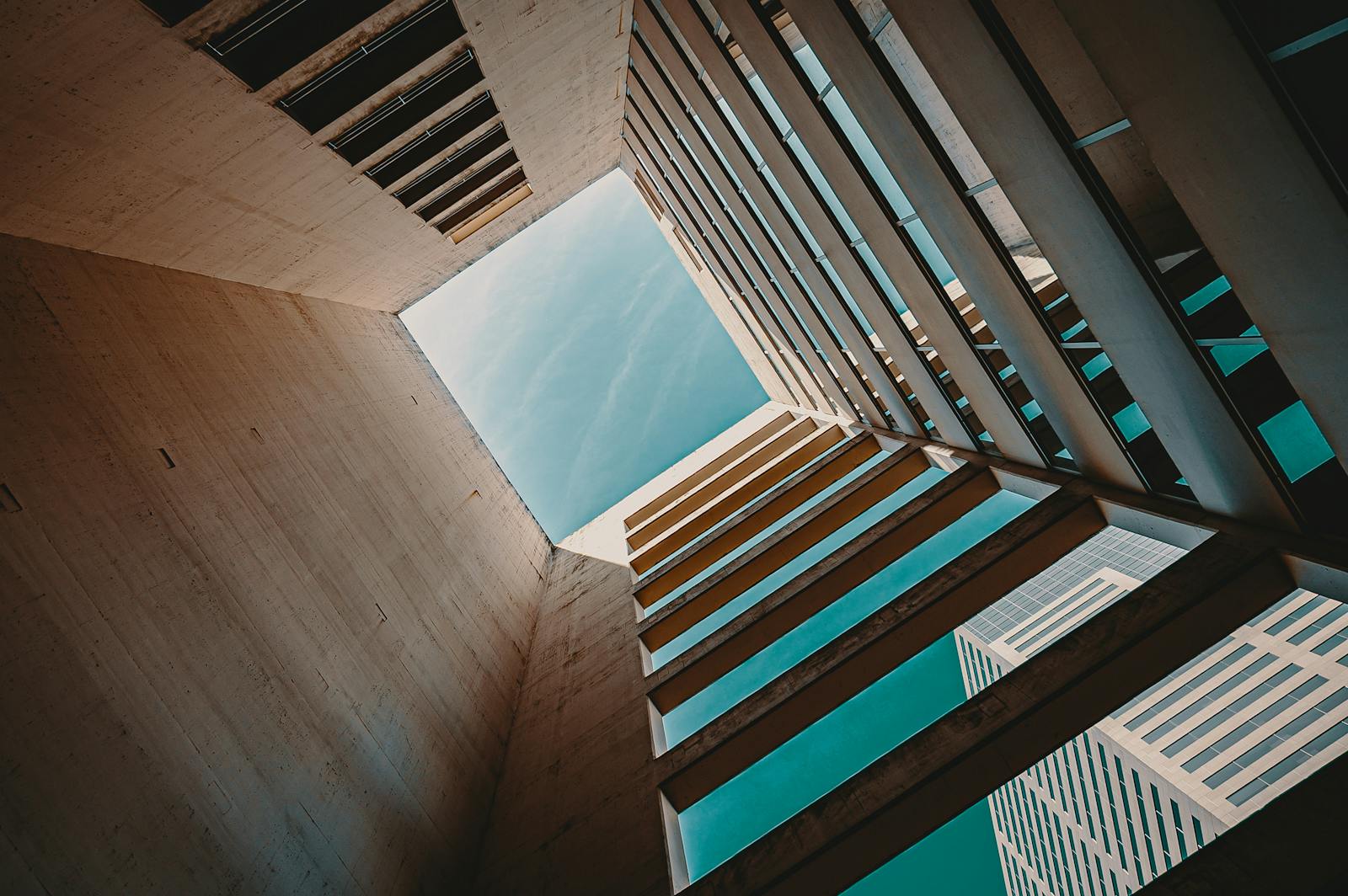 Low angle view of a modern building structure with open sky, emphasizing contemporary design and geometry.
