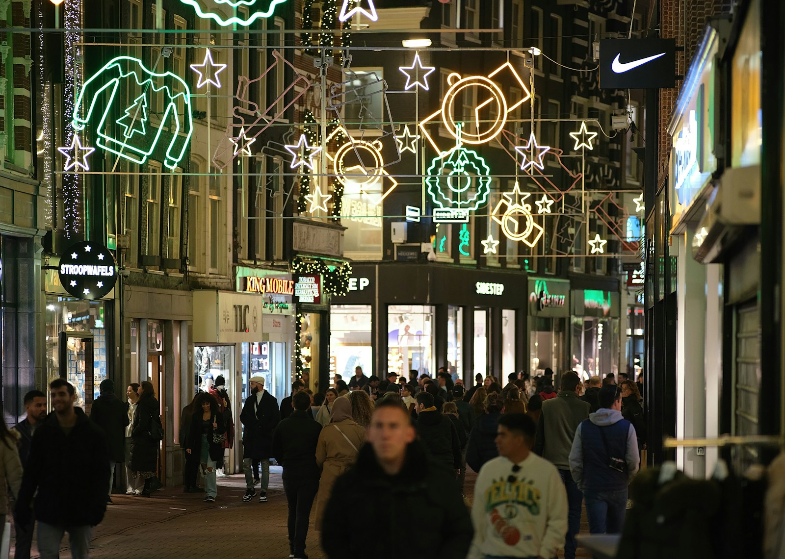 a group of people walking down a street at night