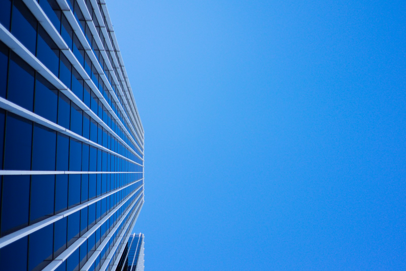 low-angle photography of curtain glass building under blue sky