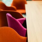 Orange and pink chairs at a wooden table.
