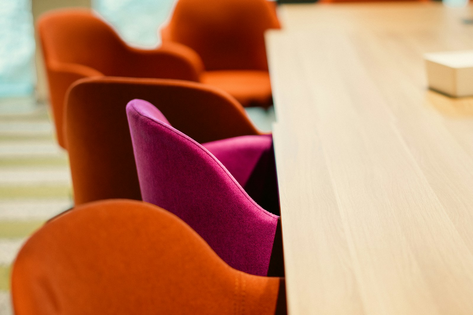 Orange and pink chairs at a wooden table.