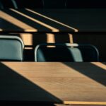 Sunlight streams through blinds onto wooden desks.