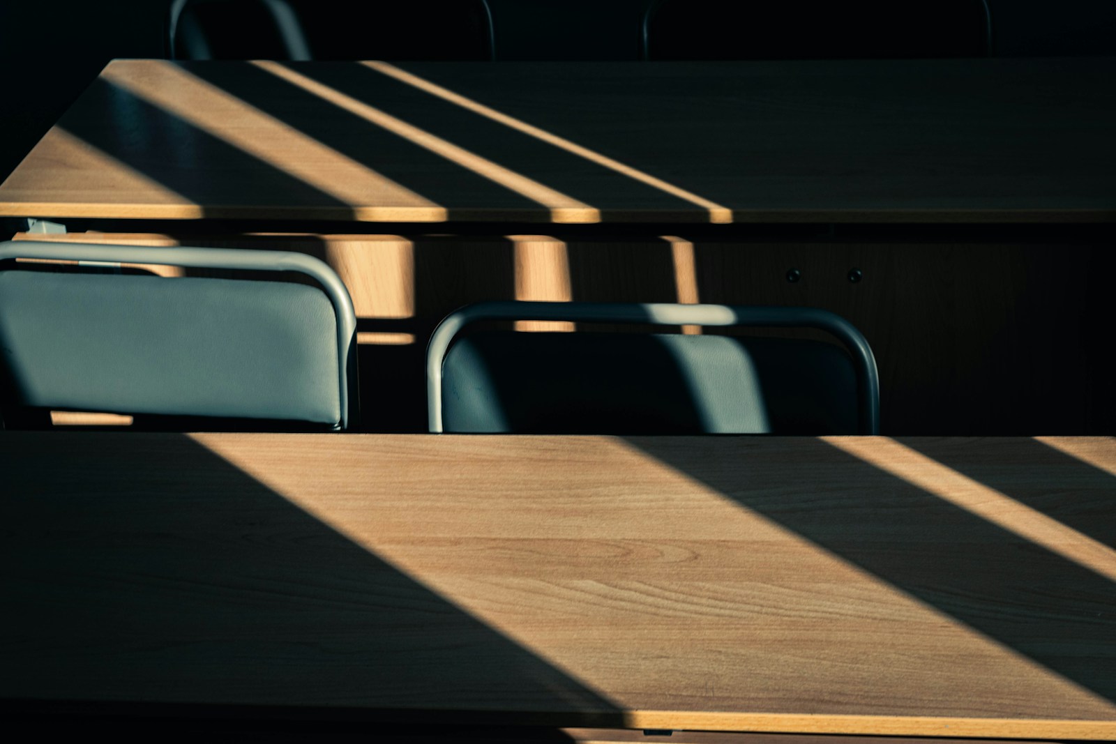 Sunlight streams through blinds onto wooden desks.