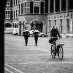 grayscale photo of woman riding bicycle on road