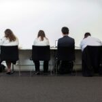 a group of people sitting at a table in front of a white wall