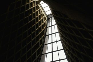 Dark, geometric architectural interior with bright central skylight.